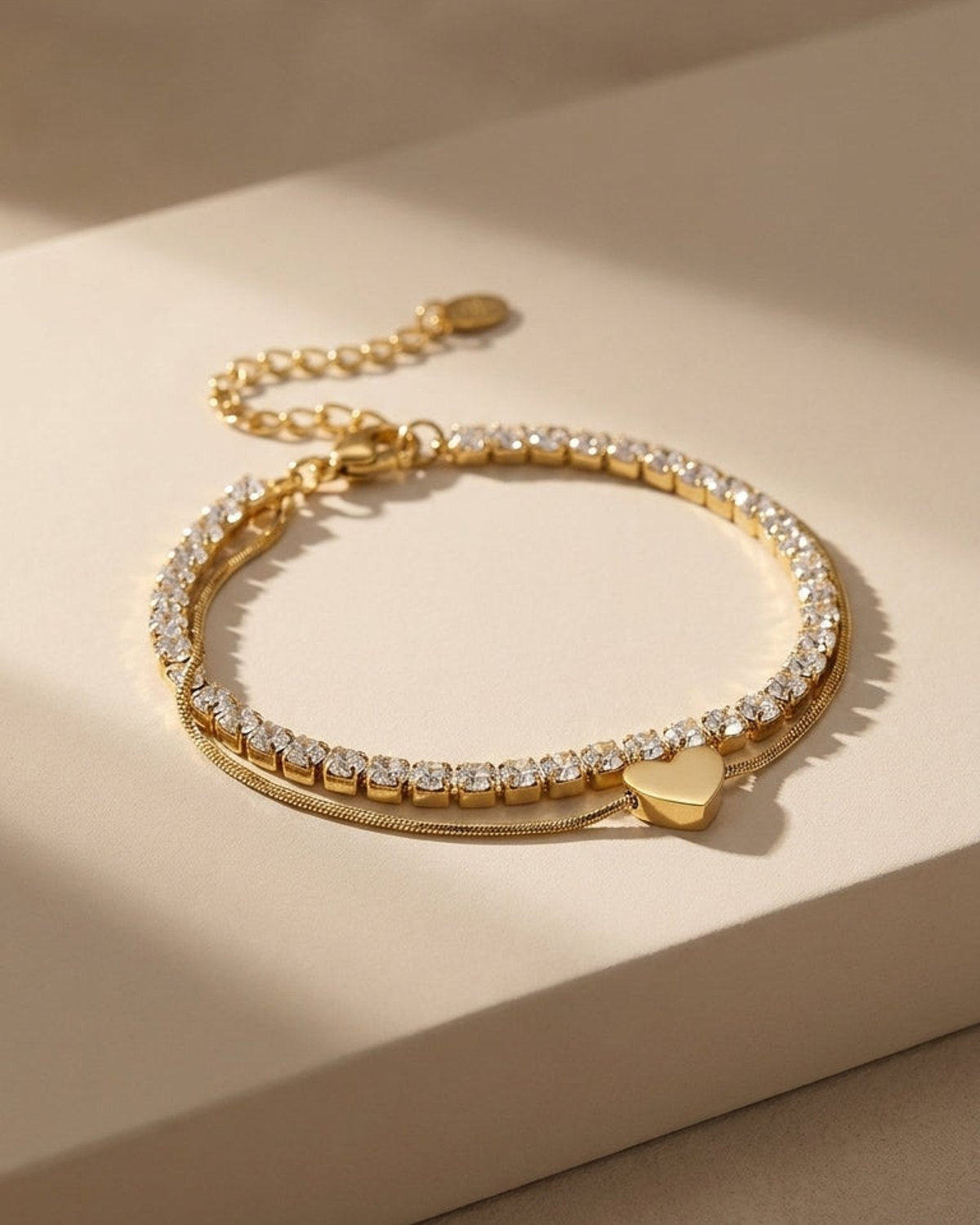 Charm Layered Bracelet featuring a gold rhinestone chain and a thin gold chain with a heart charm.