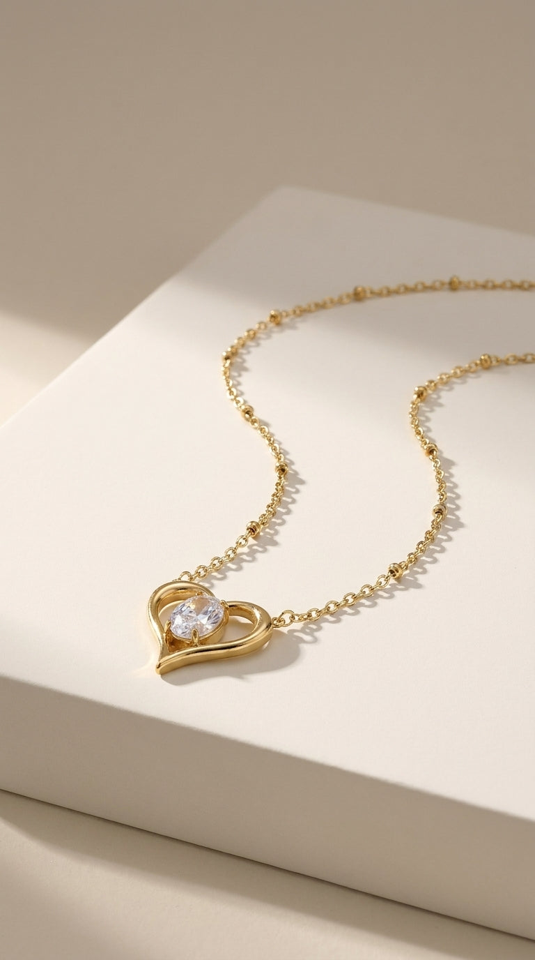 Gold stainless steel necklace with a heart-shaped pendant holding a clear, faceted stone.