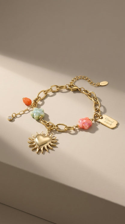 Charm Era Unlocked gold-tone chain bracelet with pastel flower charms, a heart sun pendant, and a Good Luck tag.