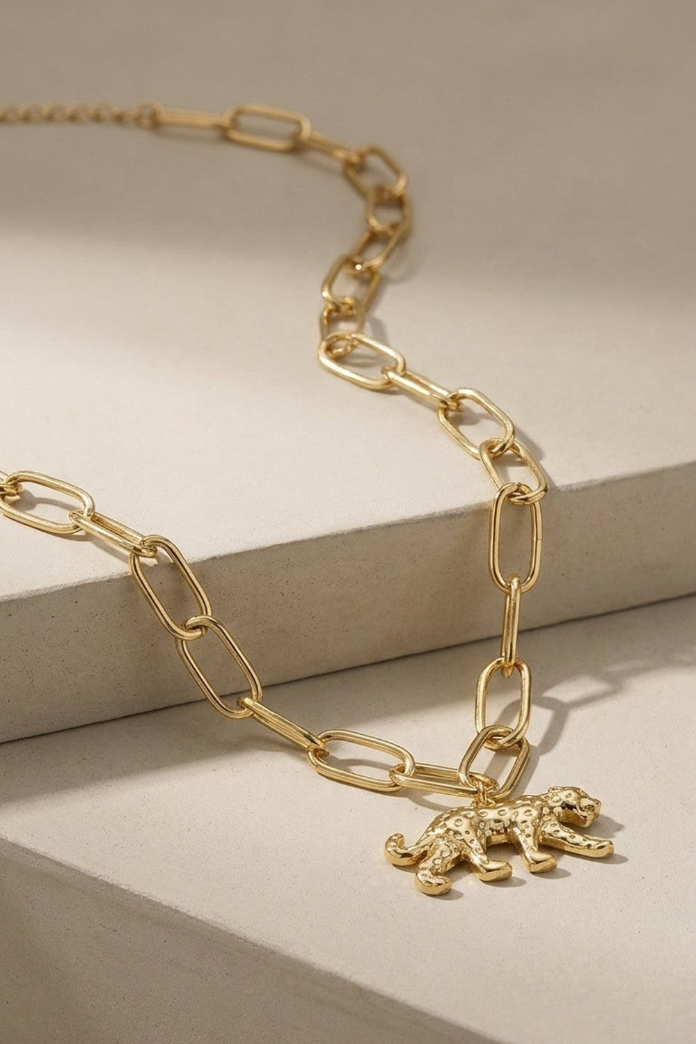 Gold chain necklace with a textured leopard pendant.