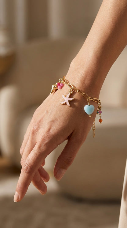 Coastal Charm gold-tone chain bracelet featuring pink starfish, blue heart, and colorful bead charms on a wrist.