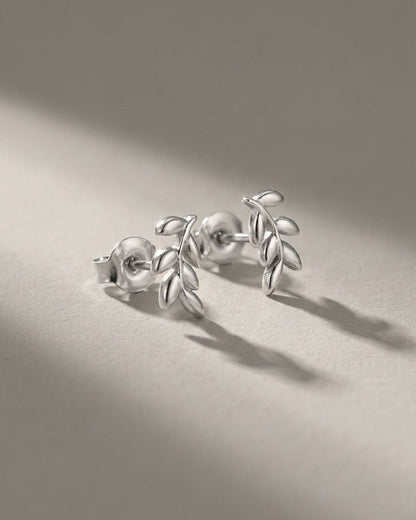 Sprout Vibe Gold earrings: polished gold-tone metal stud earrings shaped like delicate leaf sprigs.