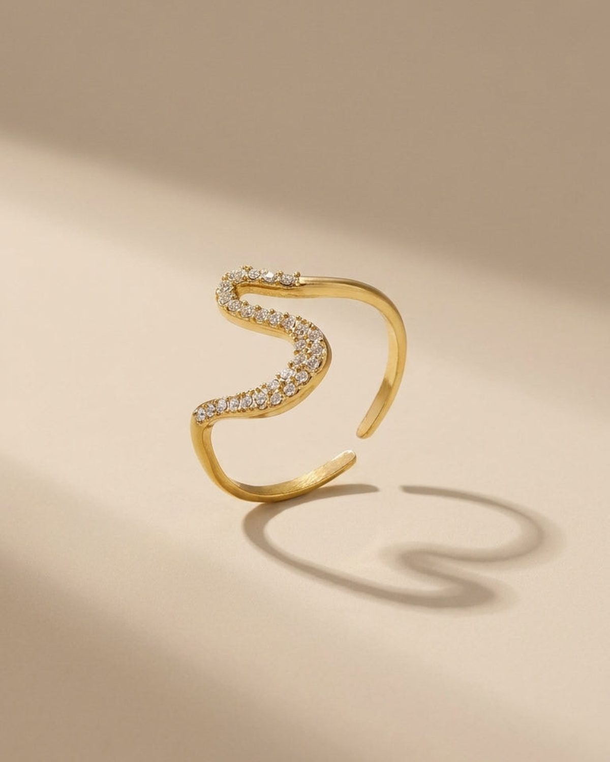 Gold Rhinestone Line Ring with an S-curve paved with rhinestones on a neutral background.
