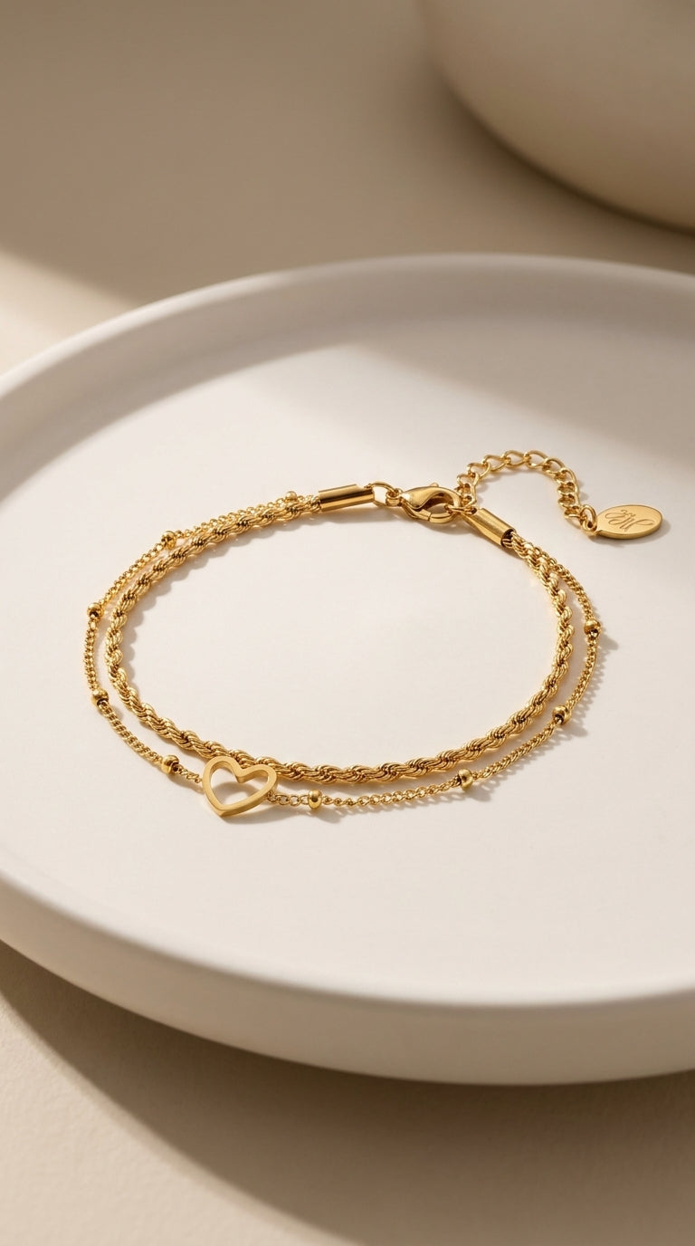 Layered gold chain bracelet with twisted rope and bead strands, featuring an open heart charm.