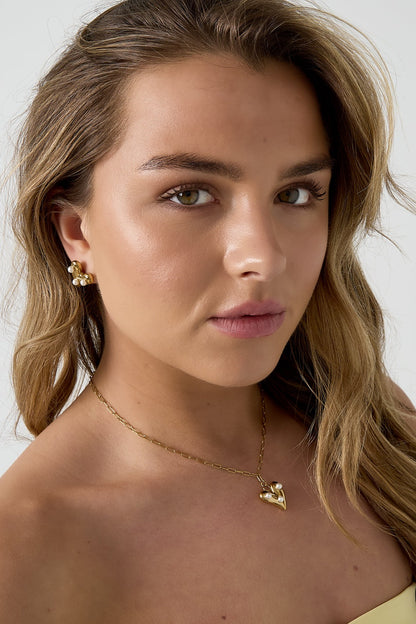 Close-up of a model wearing the gold-tone pearl heart pendant necklace with matching pearl heart earrings