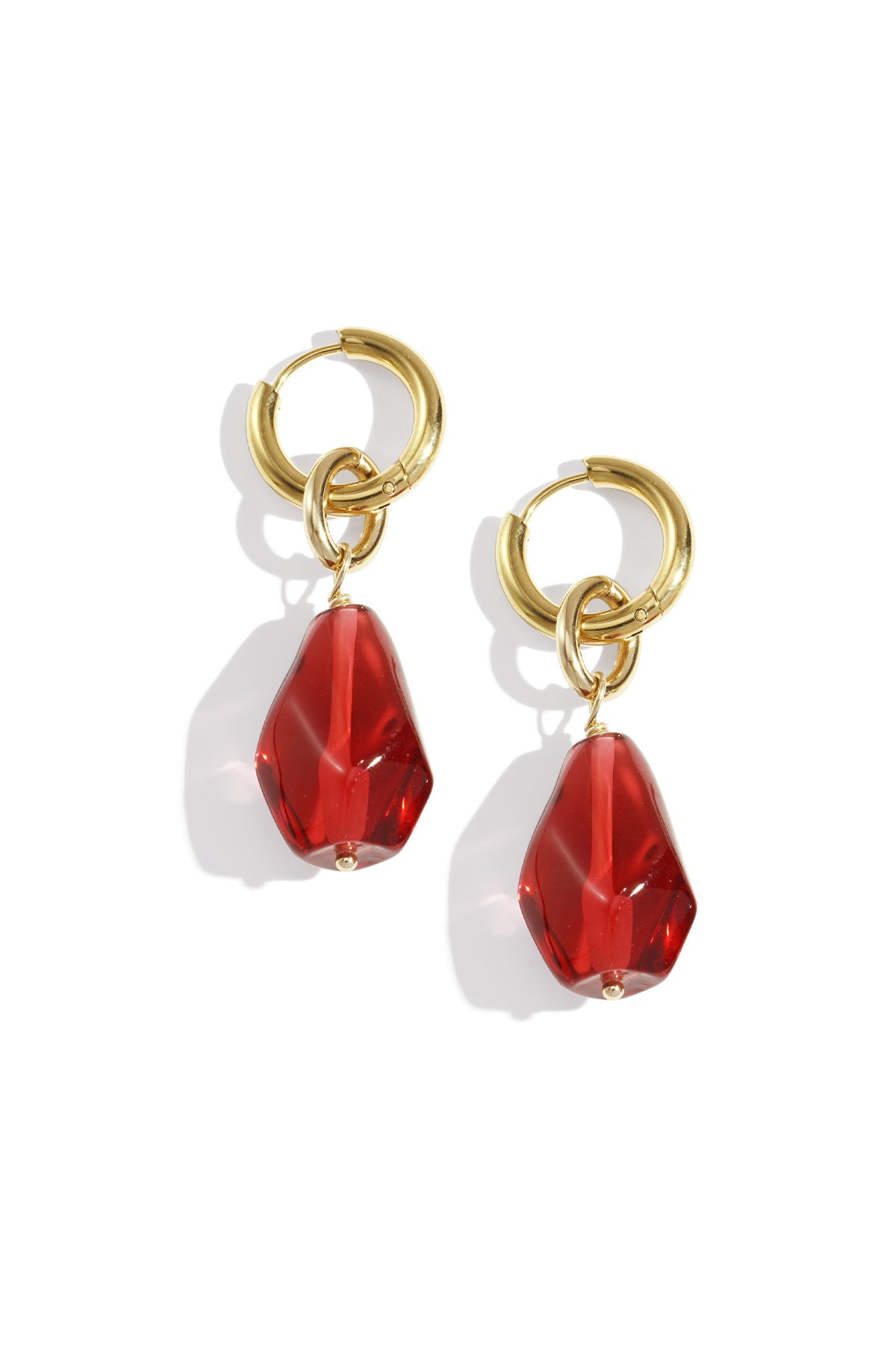 Pair of gold hoop drop earrings with irregular crimson red acrylic charms on white background