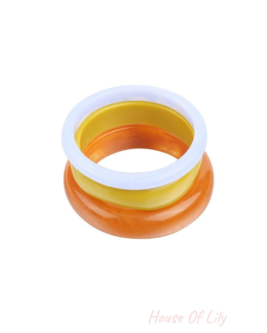 Stack of three resin bangles in light blue, yellow, and marbled orange on white background