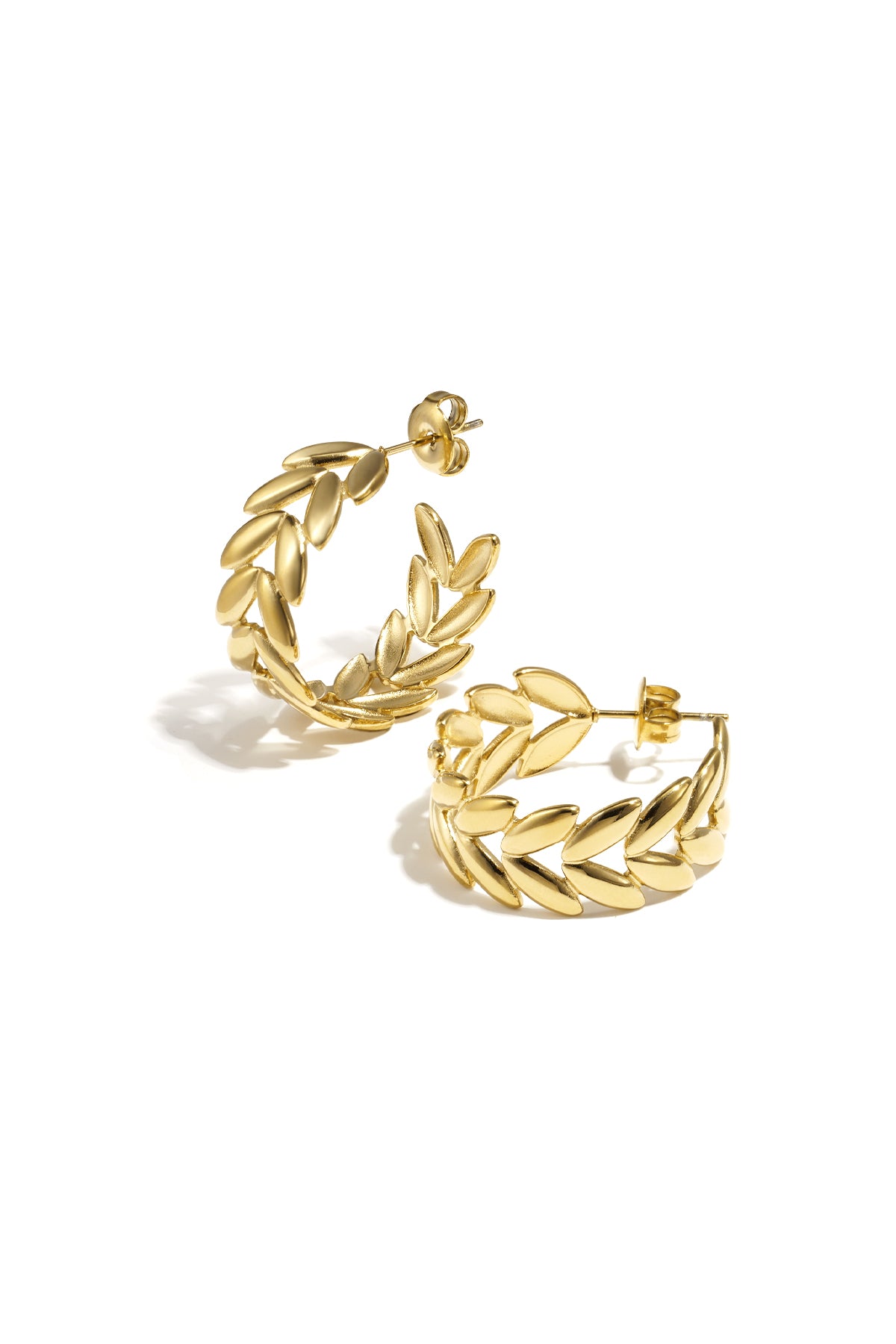 Pair of gold leaf motif hoop earrings with polished finish on white background
