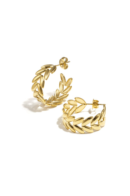 Pair of gold leaf motif hoop earrings with polished finish on white background