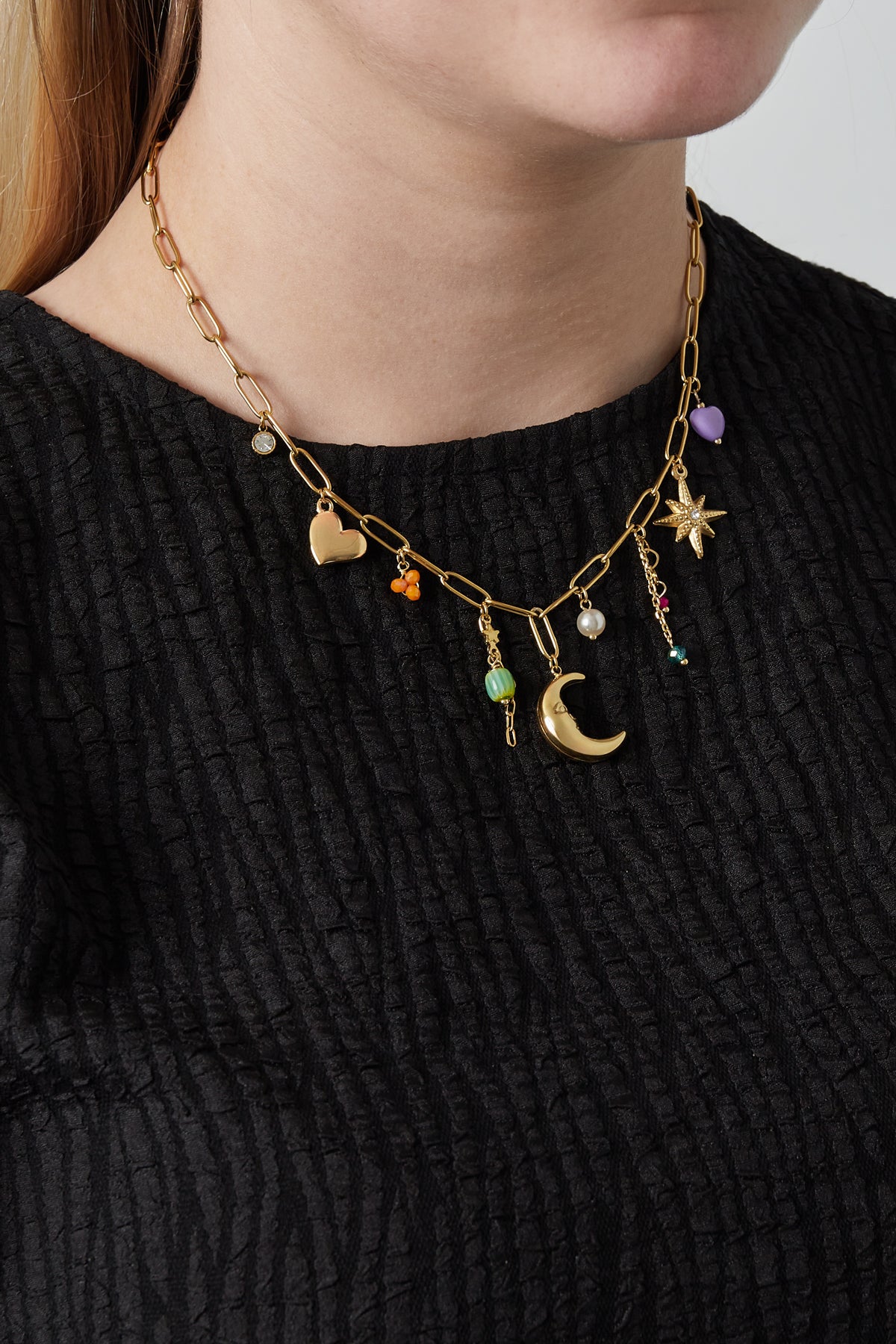 Model wearing the gold charm pendant necklace with black textured top