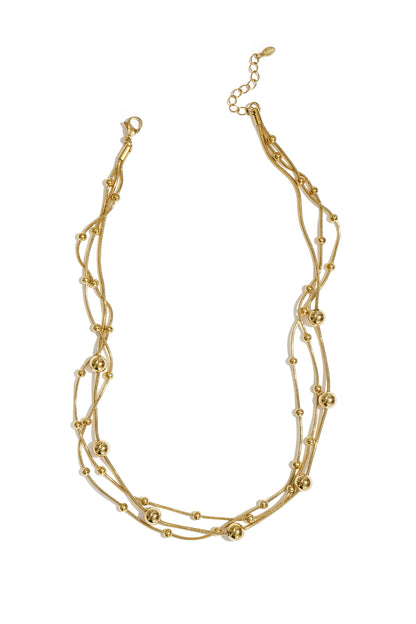 Gold multi-layered necklace with small and large beads laid flat on white background