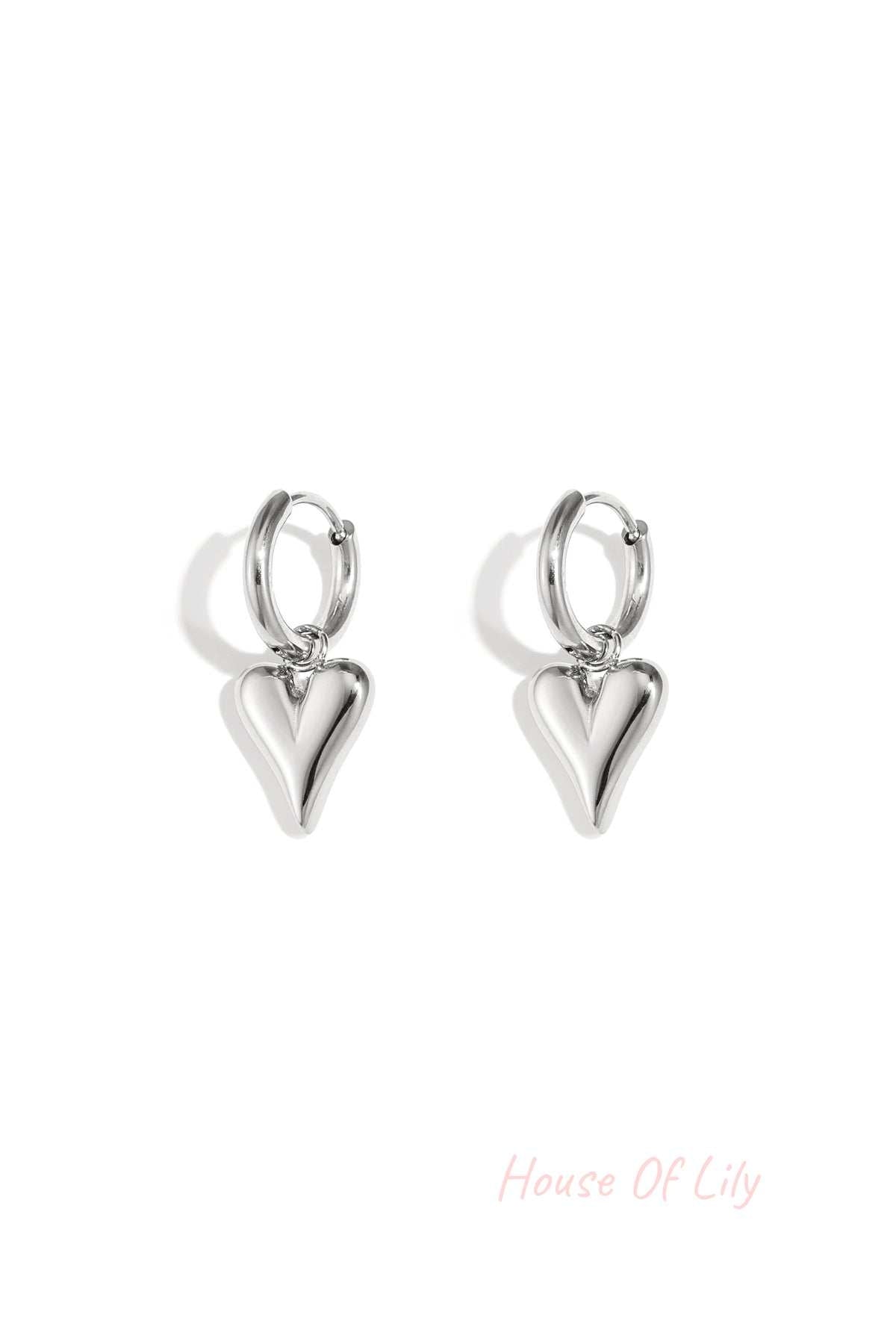 Pair of silver-tone heart-shaped drop earrings with a polished finish isolated on white background