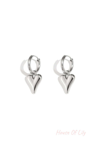 Pair of silver-tone heart-shaped drop earrings with a polished finish isolated on white background