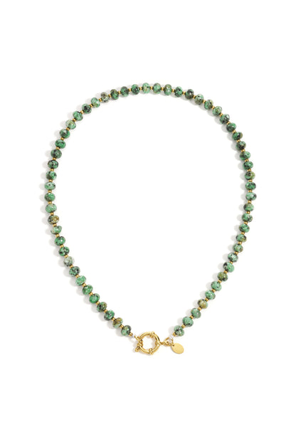 Close-up of a green stone beaded necklace with gold beads and toggle clasp