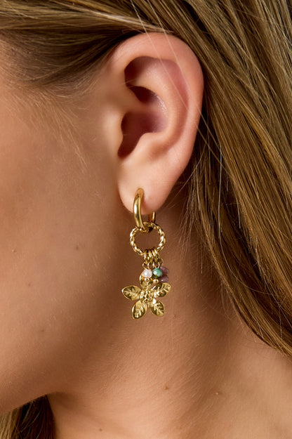 Side profile of woman showing close detail of gold floral drop earring with multicolor beads