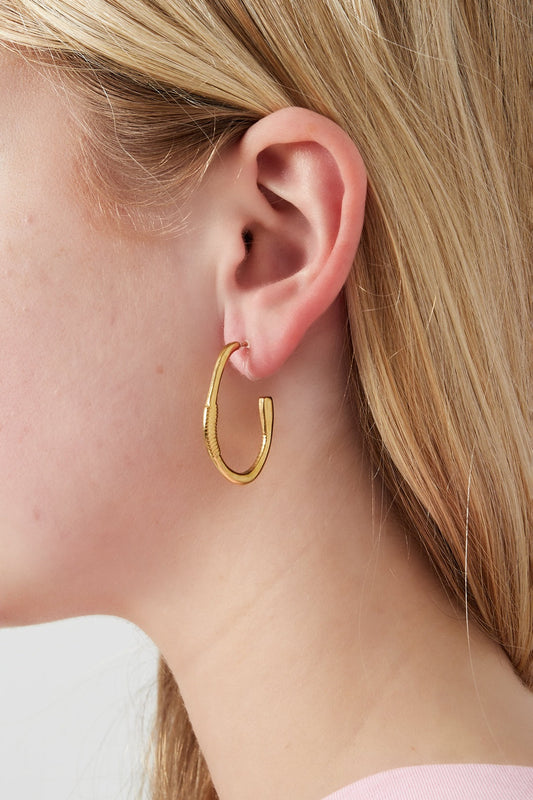 Model wearing gold textured hoop clip earrings showing fit and style