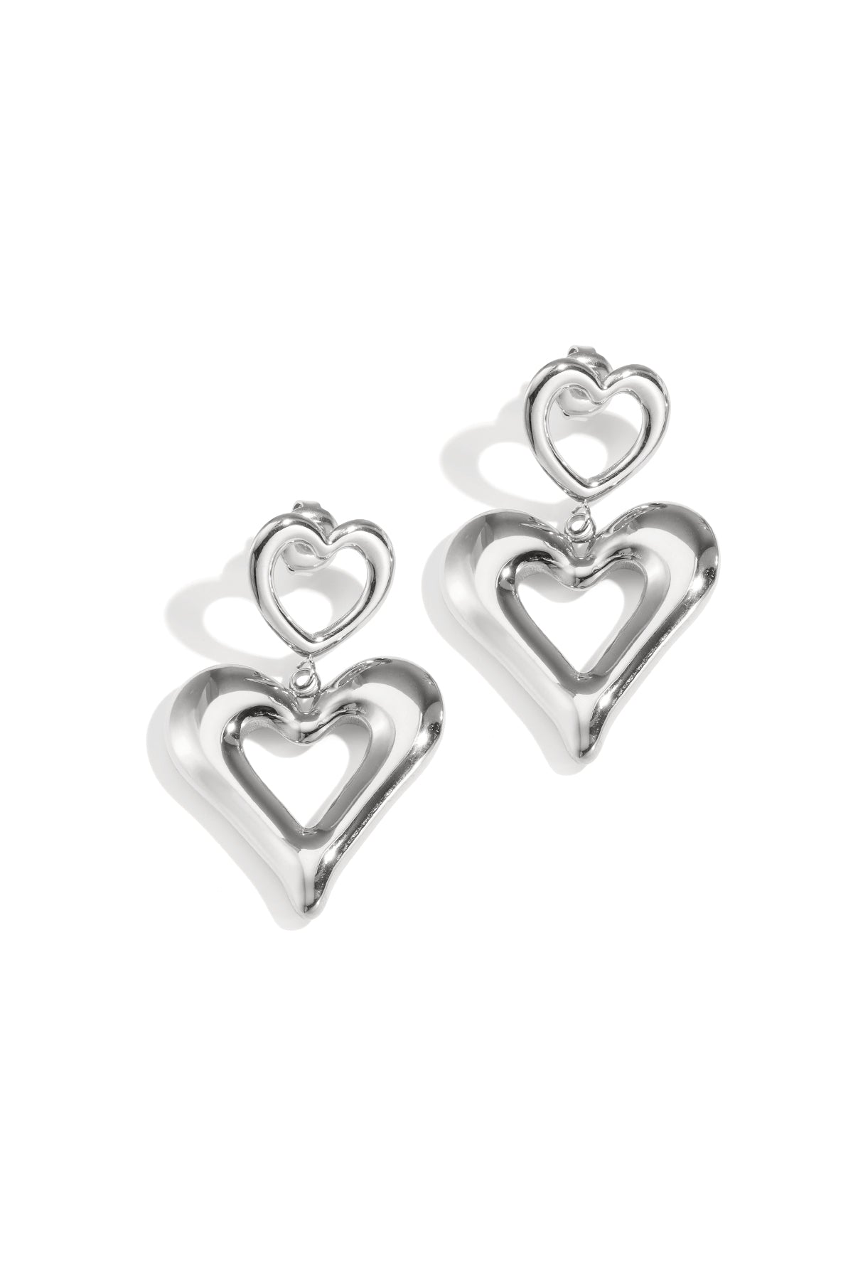 Pair of shiny silver double heart drop earrings on white background