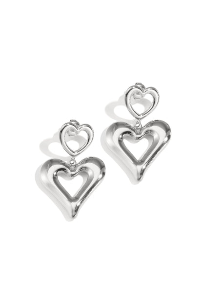 Pair of shiny silver double heart drop earrings on white background