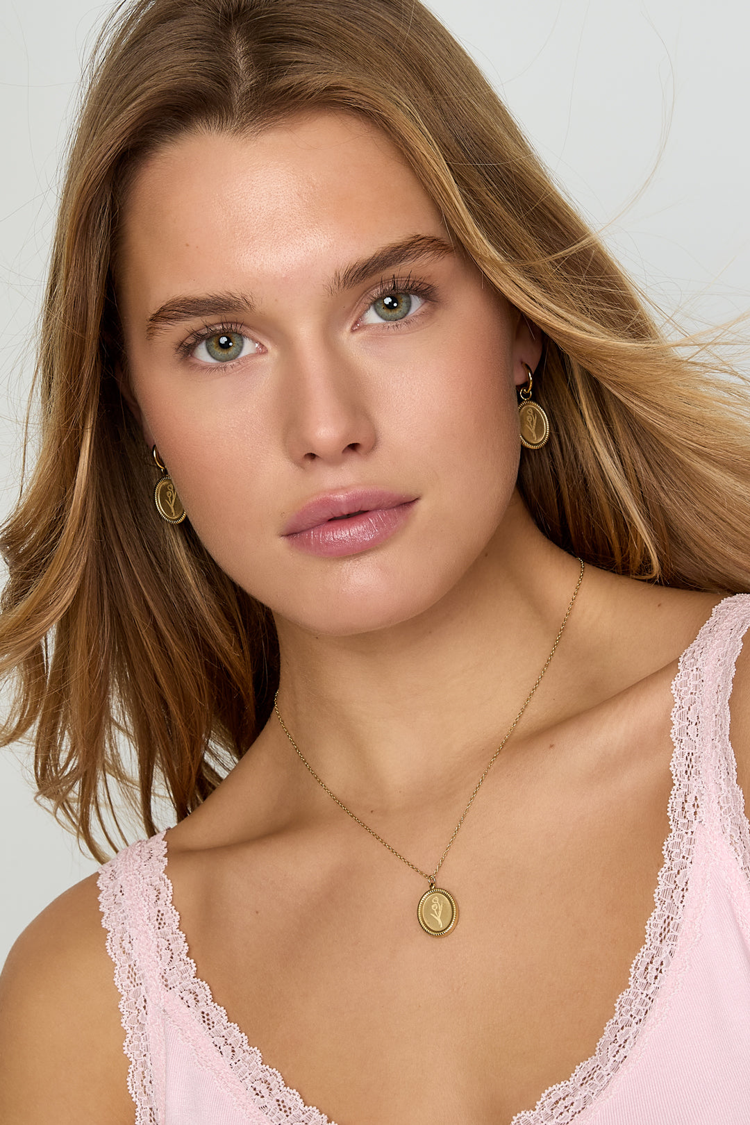 Model wearing gold tulip blossom pendant necklace and matching earrings with pink lace top