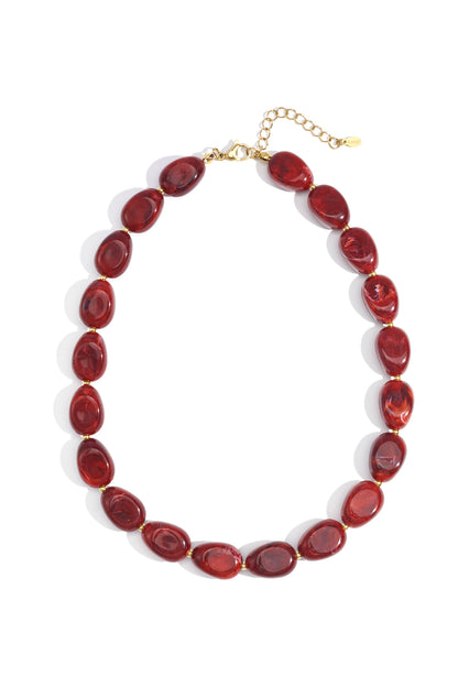 Close-up of red chunky acrylic beaded necklace with gold clasp on white background