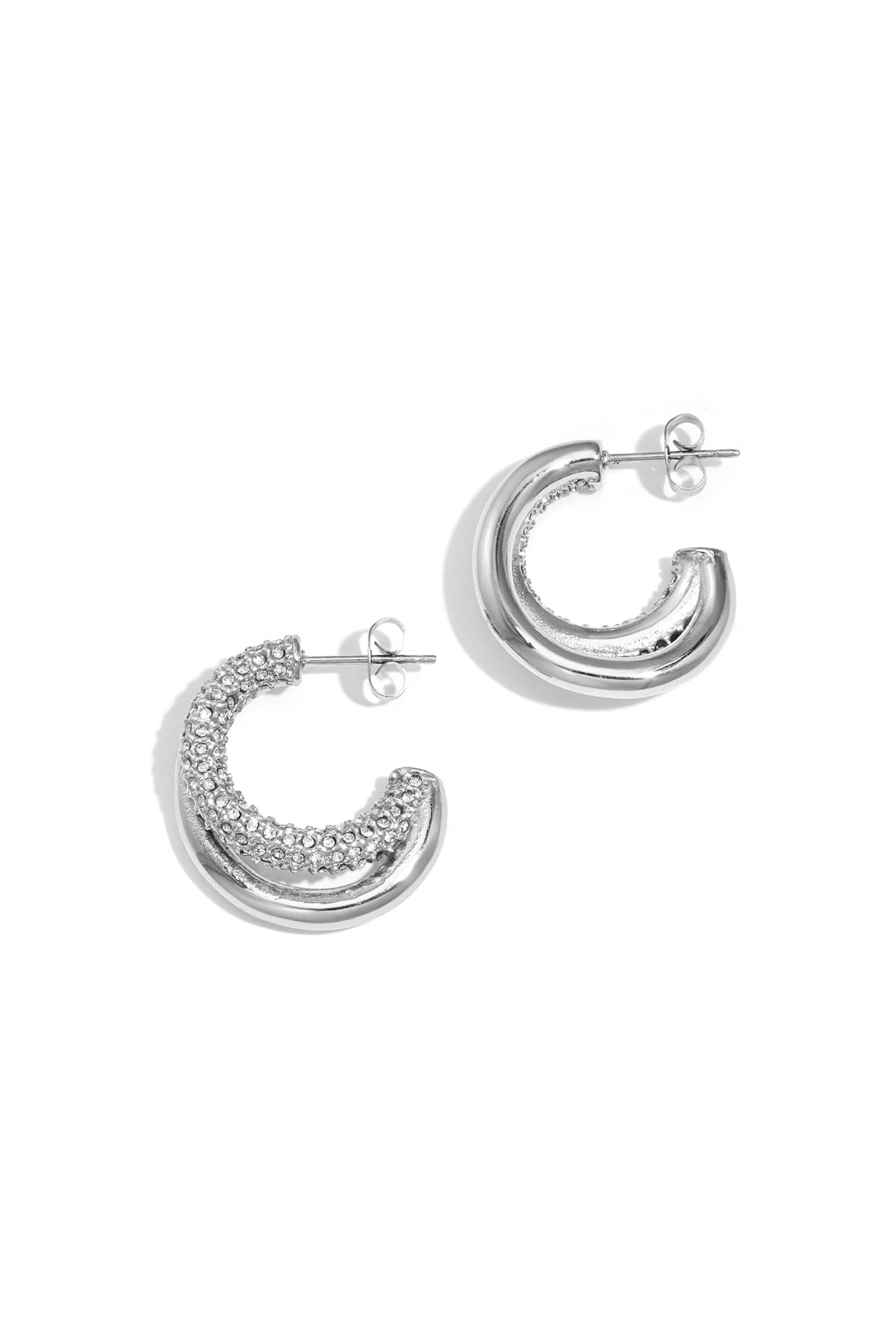 Pair of silver tone chunky hoop earrings with rhinestone detail on white background