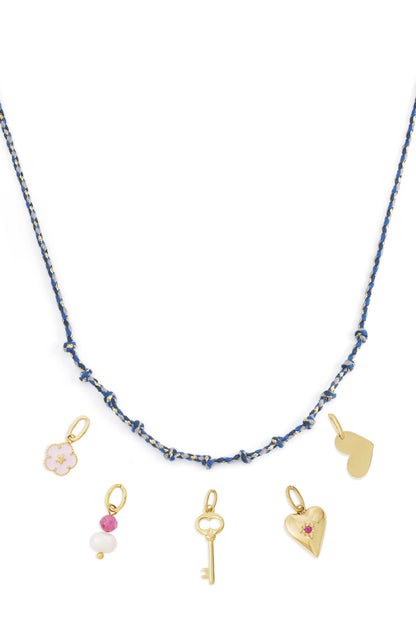 Blue knotted cotton necklace with gold charms including heart, key, pearl and flower charms laid flat on white background