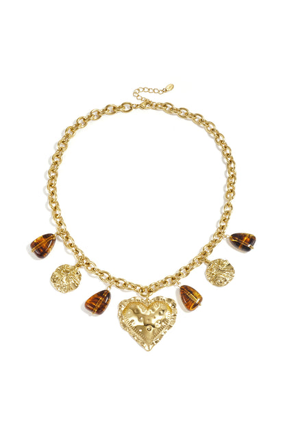 Gold-tone chunky chain necklace with hammered heart charm, hammered coin charms, and amber resin teardrop charms laid flat on white background