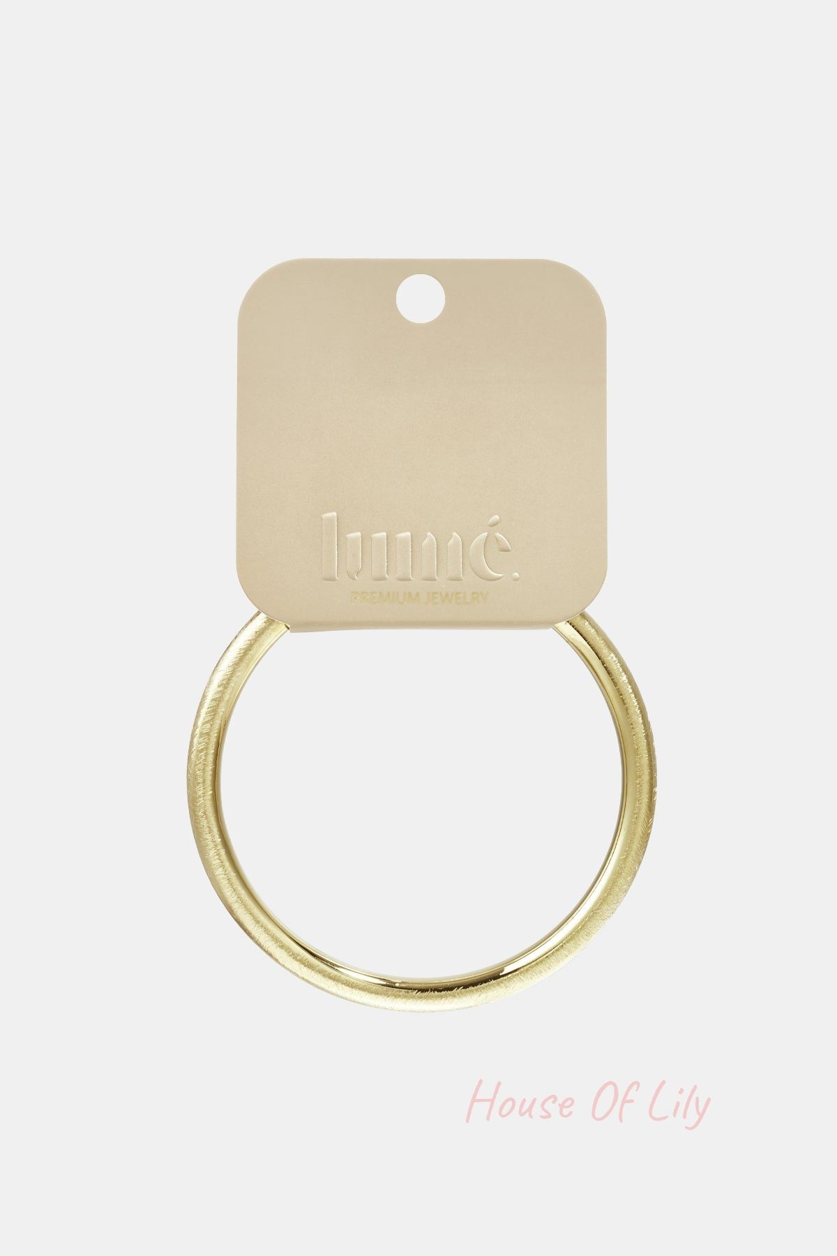 Gold-toned brushed metal circle bangle on a branded beige jewelry display card.