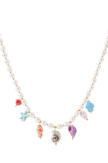 Close-up of a beaded necklace with imitation pearls and colorful ceramic sea-themed charms including starfish, fish, turtle, and shells.