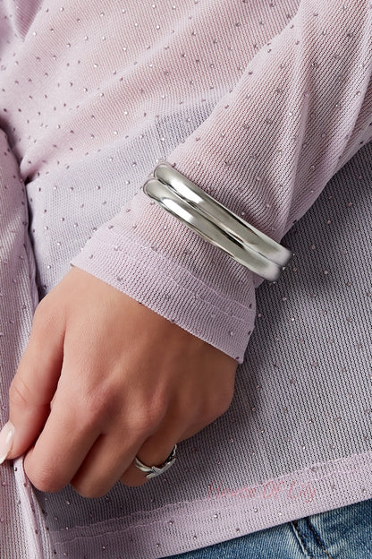 Silver double-band bangle worn on wrist, styled with a delicate purple sheer sleeve and silver ring, highlighting youthful aesthetic