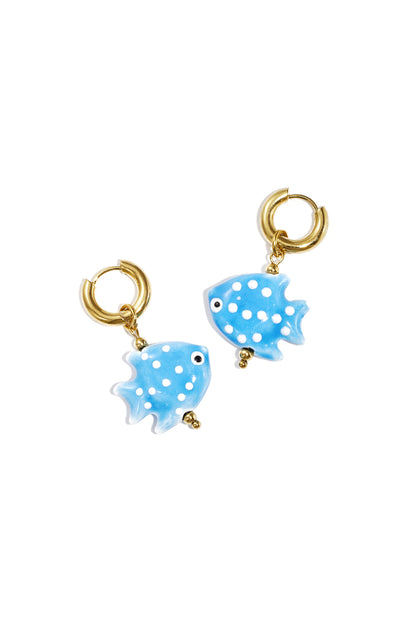 Pair of gold hoop earrings featuring baby blue fish-shaped charms with white polka dots on white background