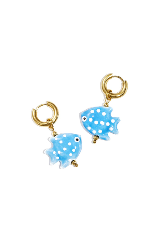 Pair of gold hoop earrings featuring baby blue fish-shaped charms with white polka dots on white background