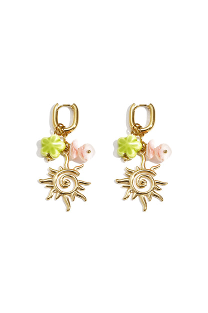 Gold-tone sun charm drop earrings with green four-leaf clover and pink bead charms on a white background