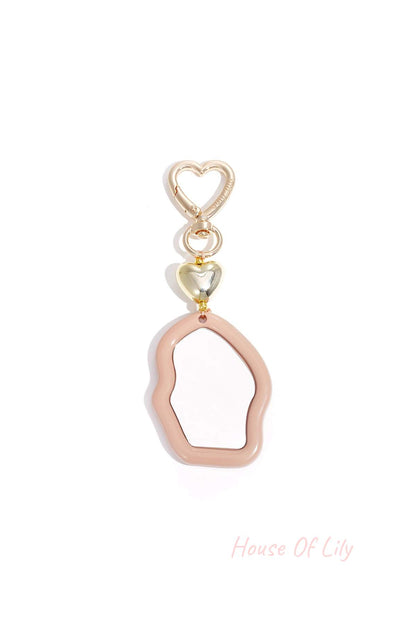 Blush pink acrylic irregular mirror charm with gold heart clasp on white background