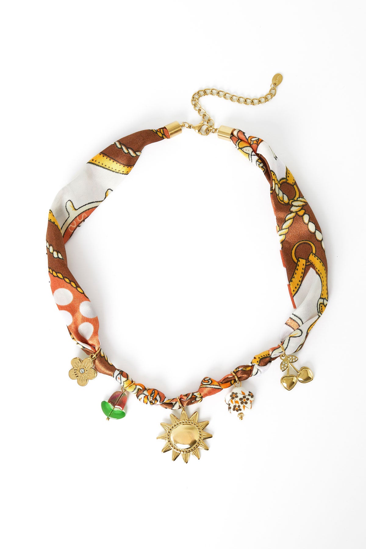 Patterned fabric charm necklace with gold sun, flower, cherry, and bead charms laid flat