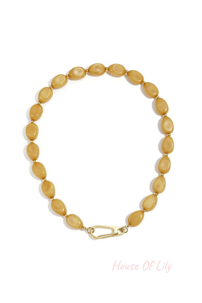 Mustard yellow acrylic beaded necklace with small gold beads and gold carabiner clasp shown on white background
