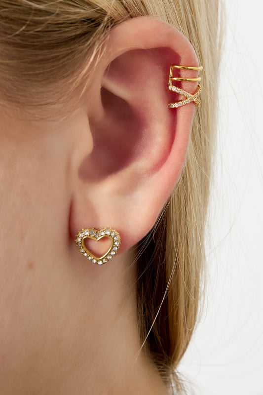 Model's ear wearing a gold-tone crisscross crystal ear cuff paired with a heart-shaped crystal stud earring