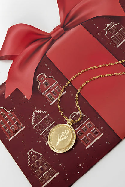 Gold tulip blossom pendant necklace resting on festive red gift bag with ribbon
