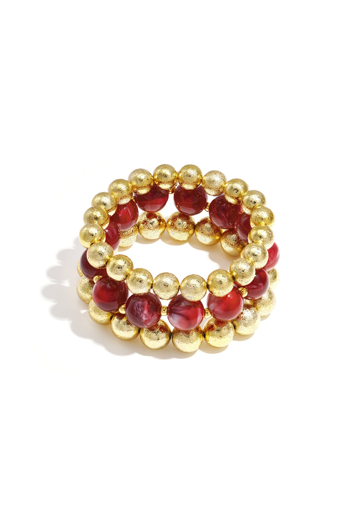 Set of three beaded bracelets with red marbled beads and textured gold spheres on white background