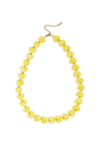 A yellow heart-beaded necklace with small gold-tone metal spacers on a gold chain, isolated on a white background.