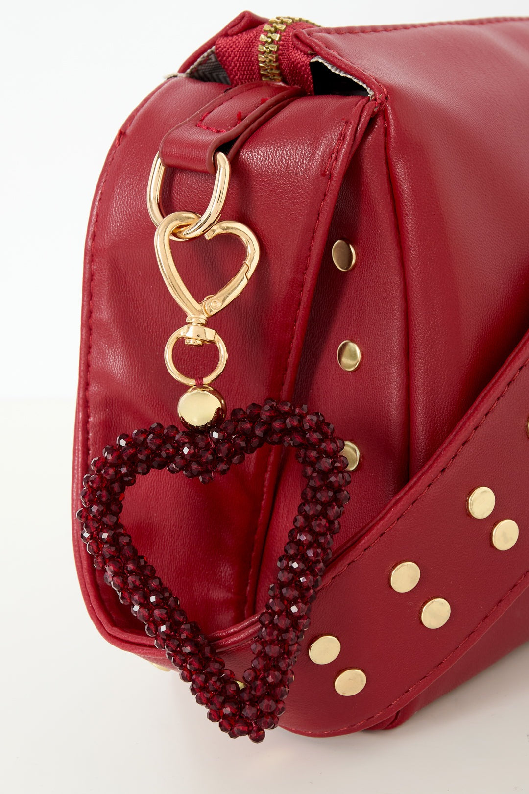 Dark crimson beaded heart keychain clipped to red studded handbag strap