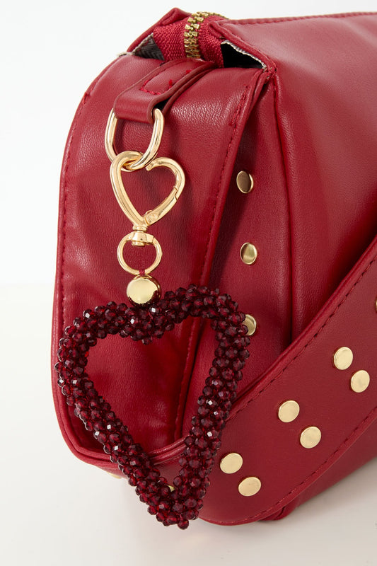 Dark crimson beaded heart keychain clipped to red studded handbag strap