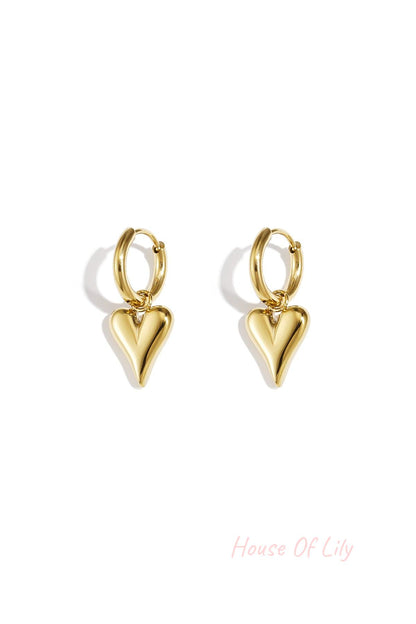 Pair of gold-tone heart-shaped drop earrings with smooth, polished finish against a white background