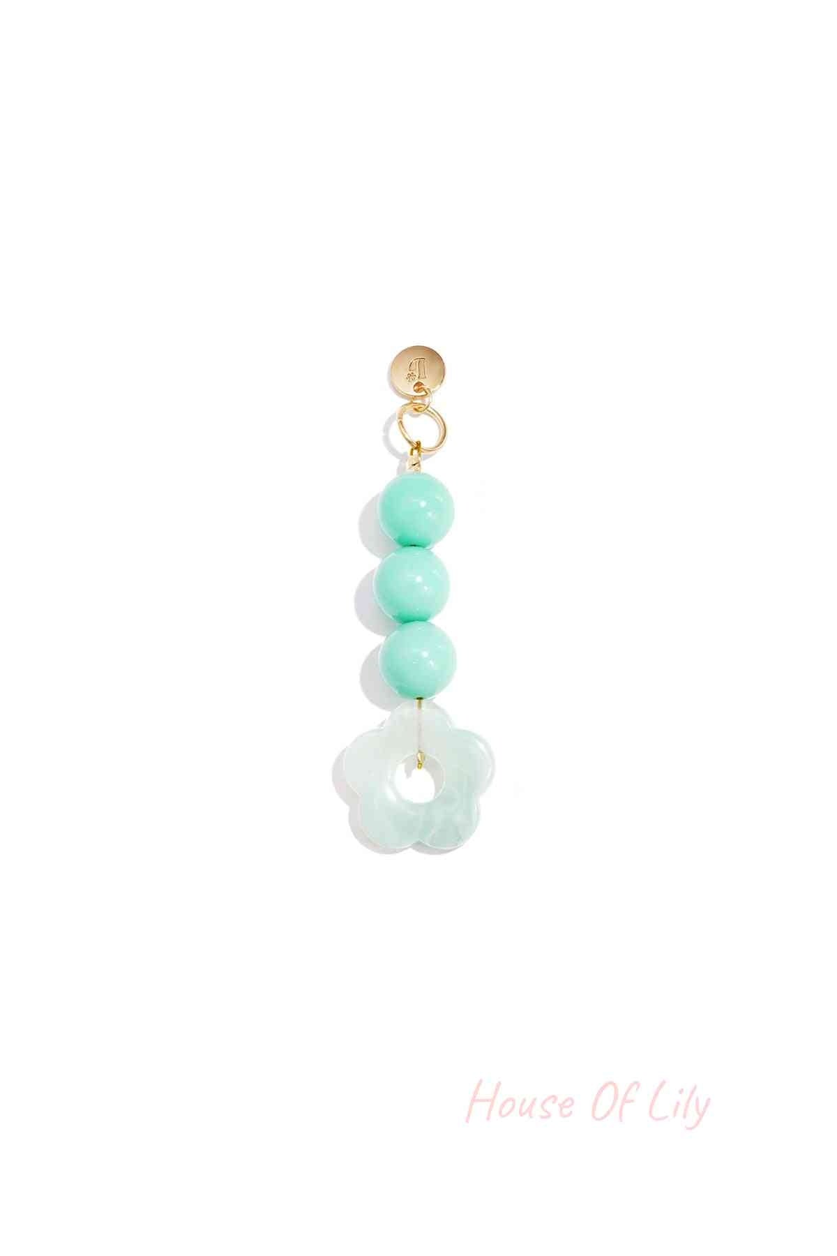 Mint green translucent acrylic flower bag charm with three round mint green beads hanging from a gold clasp on white background