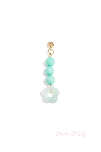 Mint green translucent acrylic flower bag charm with three round mint green beads hanging from a gold clasp on white background