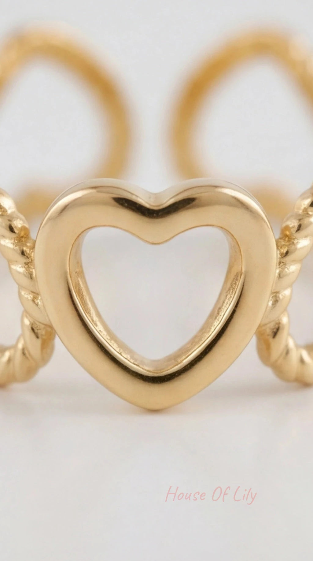 Gold heart ring with a delicate rope-textured band, featuring a polished open heart motif in the center.