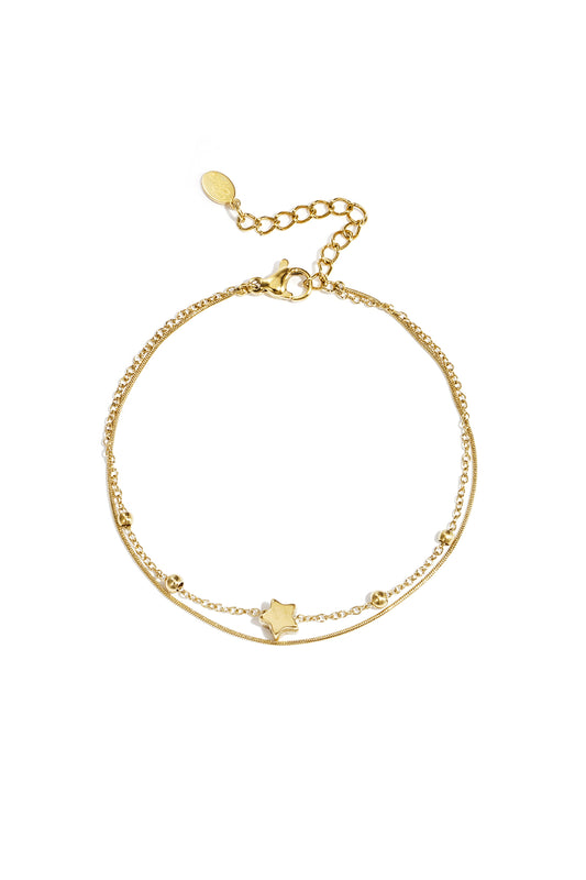 Gold-tone delicate double chain bracelet with star charm, laid flat on a white background showing lobster clasp and extension chain.