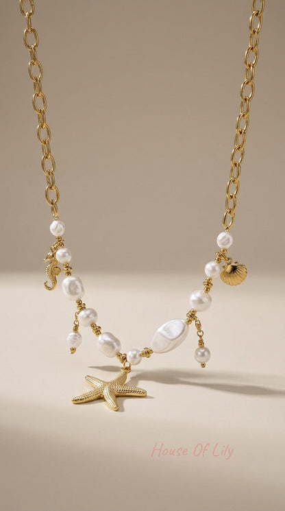 Gold chain necklace with white freshwater pearls and gold charms: a starfish, seahorse, and seashell.