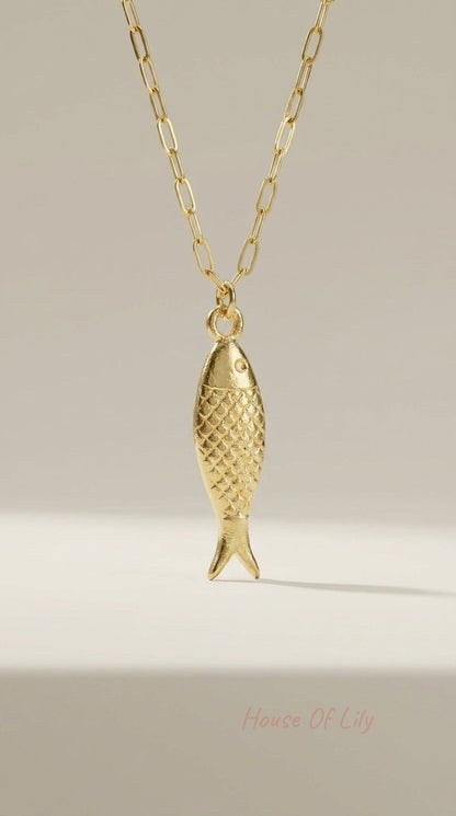 Gold-toned necklace featuring a textured, fish-shaped pendant on a dainty elongated paperclip chain.
