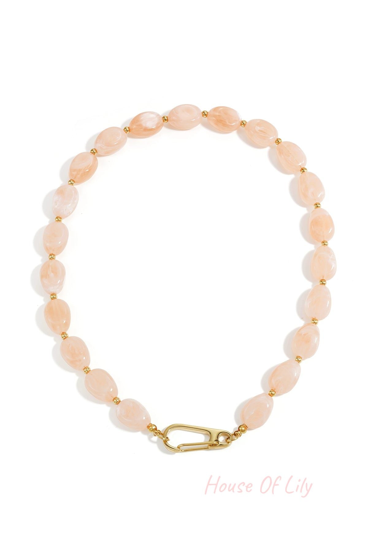 Close-up image of a blush pastel acrylic beaded necklace with gold-tone clasp laid flat on white background